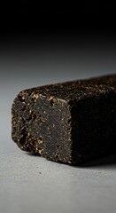 Close-up of a dark, compacted block of hashish resting on a plain surface, exhibiting its characteristic texture and color variation ,brown ,problem ,contraband