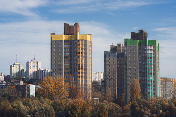 Obraz premium Urban skyline with high-rise apartment buildings amid autumn trees and clear blue sky