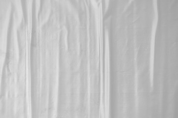 Obraz premium plastic transparent cellophane bag on white background. The texture looks blank and shiny. The plastic surface is wrinkly and tattered making abstract pattern