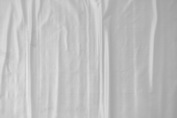 plastic transparent cellophane bag on white background. The texture looks blank and shiny. The plastic surface is wrinkly and tattered making abstract pattern