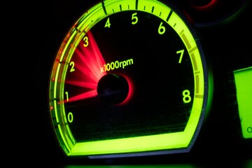 Close-up of glowing car tachometer with motion blur showing high RPM acceleration.