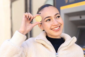 Young moroccan girl  at outdoors holding a Bitcoin and looking up