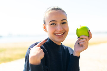Young moroccan girl  at outdoors holding an apple with happy expression