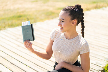 Young moroccan girl holding a passport at outdoors with happy expression