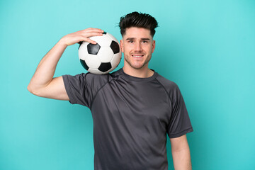 Young caucasian man isolated on blue background with soccer ball