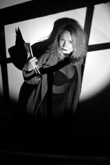 A stylish woman in a coat stands on the stairs. Black and white noir style.