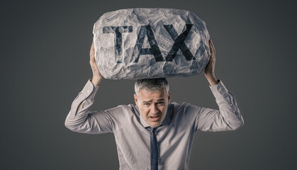 A Businessman Struggling to Hold a Heavy Boulder Marked &ldquo;TAX&rdquo; Above His Head