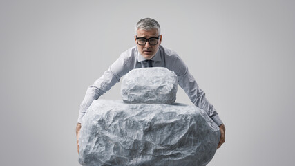 A Businessman Struggling to Hold Two Heavy Boulders in His Hands