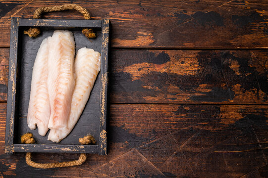 Fresh fish meat, Raw cod loin pieces without skin in wooden tray. wooden background. top view