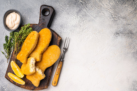 Deep fried Fish fingers on wooden board. white background. top view