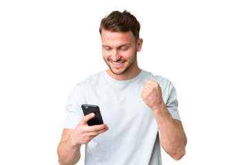 Young handsome caucasian man over isolated chroma key background using mobile phone and doing victory gesture