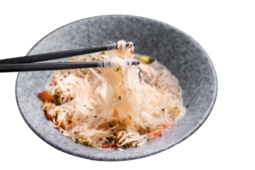 Asian glass noodles with crab meat and vegetables in a bowl. black background. top view