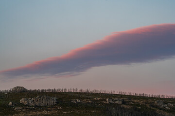 Serene Sunset Over Rocky Landscape with Pink Clouds