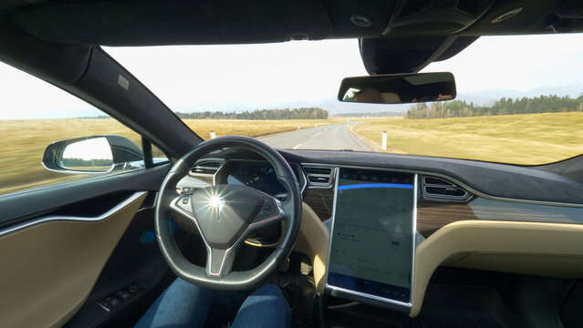 POV: Tesla logo on steering wheel shines brightly while car drives down road