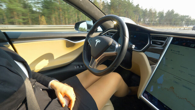CLOSE UP: Elegantly dressed woman cruising to work in high tech autonomous car.