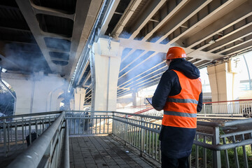 Safety worker noting details under steaming bridge