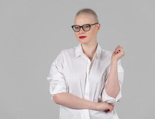 Portrait of a beautiful young caucasian woman with shaved head. Female cancer survivor. Smiling with Glasses Posing Confidently in a Studio. A portrait showcasing strength. Model Has Glaucoma