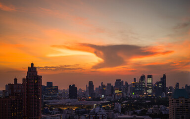 Fototapeta premium Dramatic sunset over modern city skyline - Golden sunset light illuminating a modern city skyline with dramatic clouds and evening atmosphere 