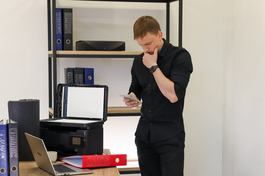 Man pondering with hand on chin holding phone