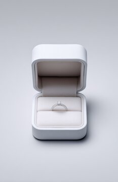 Open White Ring Box with Diamond Engagement Ring on Gray Background