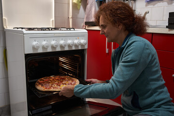 Woman taking pizza from oven © Xalanx