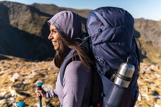 Radiant trekker carrying full pack across expansive alpine terrain