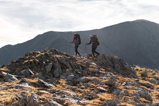 Aligned hikers traversing exposed ridge in vast mountain silence
