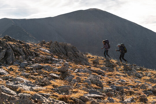 Hiking wanderers stepping carefully across windswept alpine crest