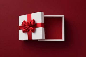 Minimalist open white gift box with red bow on a solid dark red background, top down view