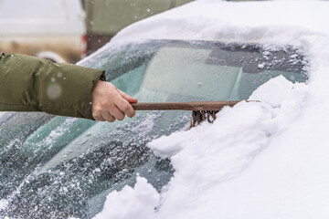 Removing snow from car windshield.