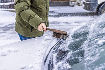 Removing snow from car windshield.