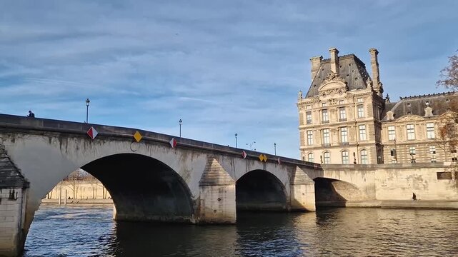 Paris, France - December 10, 2025: View from a cruising boat along the Seine River to the historic Pont Royal bridge, the ornate facade of the Louvre Museum and Grande Roue de Paris Ferris wheel