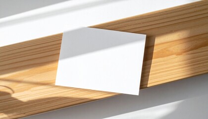 Clean blank white card mockup on a natural wooden surface bathed in sunlight, featuring crisp shadows for elegant branding and design presentation