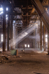 Abandoned factory interior with steel beams and light rays
