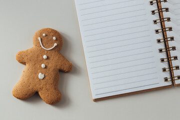 Gingerbread Man Cookie Next to Blank Notebook on a Light Surface