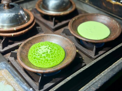 Traditional Indonesian pandan serabi cooking on clay mold using traditional stove. December 20, 2025 - Tangerang, Indonesia.