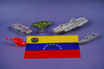The flag of Venezuela is surrounded by American military equipment. Confrontation, conflict.