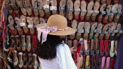 young woman street shopping in Mumbai, she is looking at beautiful handmade sandals and chappals on Fashion street, vertical video