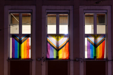 Rainbow flags displayed in illuminated windows of historic building at night, Germany, Augsburg, 19 December 2025