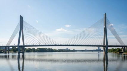 Obraz premium Suspension bridge over calm river under clear blue sky in urban landscape
