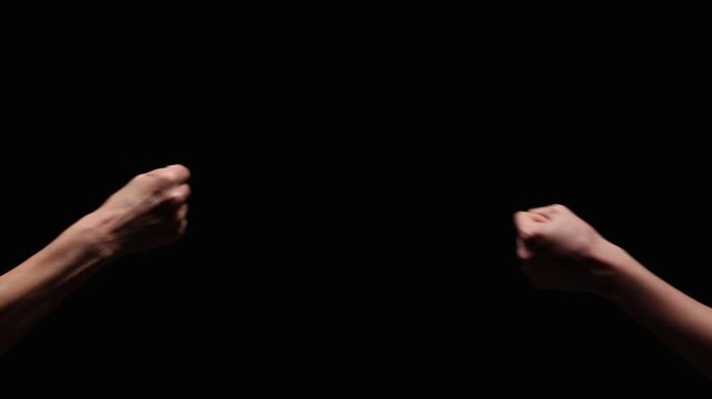 Two outstretched arms meet in a fist bump against a dark, black background, symbolizing unity and support. Significant copy space