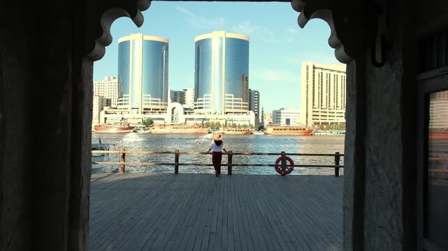 woman enjoying at Al seef Dubai with old Dubai skyline view and Abra boats, Cinematic travel video in 4k pro res 