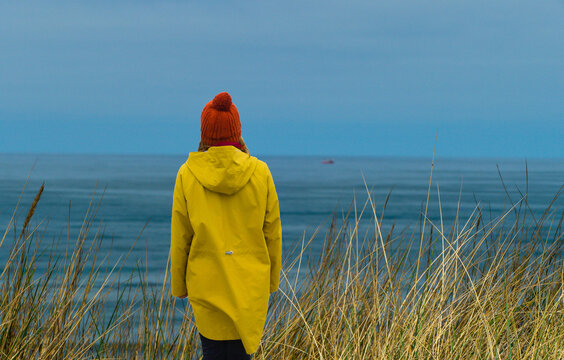 Touristin mit gelbem Regenmantel blickt auf Meer Nordsee
