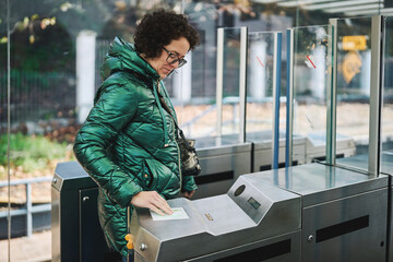 Woman scanning transit card at electronic turnstile outdoors
