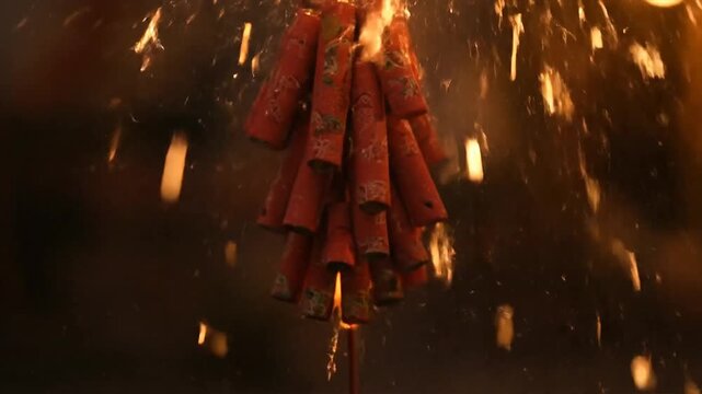 A bundle of firecrackers exploding in mid-air, surrounded by sparks and flames, captured from a low-angle viewpoint