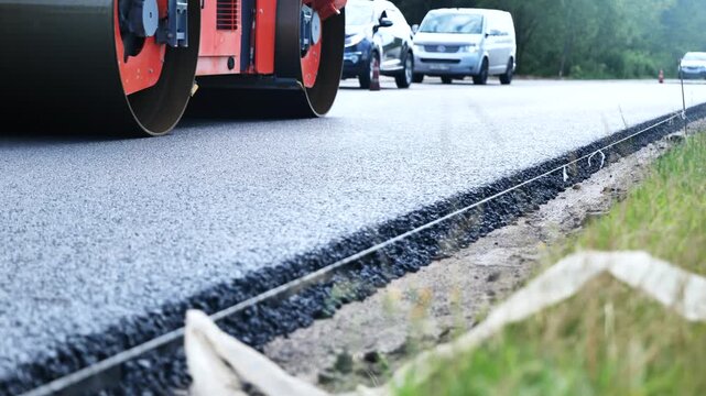 Asphalt roller compacting a new layer of tarmac on a highway under construction
