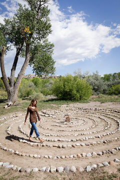 Ojo Caliente, New Mexico, United States.  Woman walking through a stone circle on the ground - summer time with clouds. 