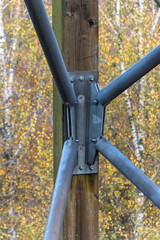 Diagonal metal pipes bolted to a wooden support.