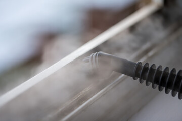 Cleaning the window. Steam device removes dirt from the plastic window frame.