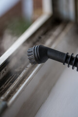 Cleaning the window. Steam device removes dirt from the plastic window frame.